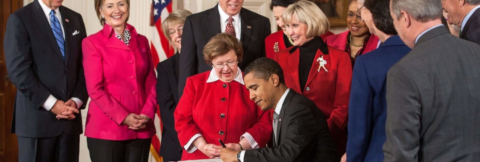 A photo of Barack Obama signing legislation that enforces/encourages equal pay.