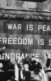 A photo of people in front of a monument that says "War is peace. Freedom is slavery."