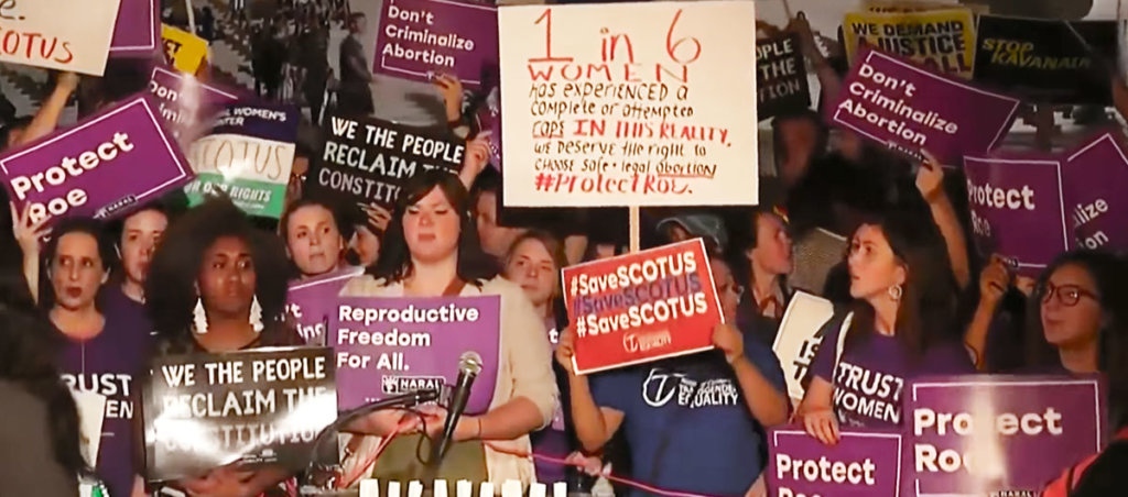 A photo from an abortion rights protest where people, largely women, are holding signs with messages like "Protect Roe" and "#SaveSCOTUS"