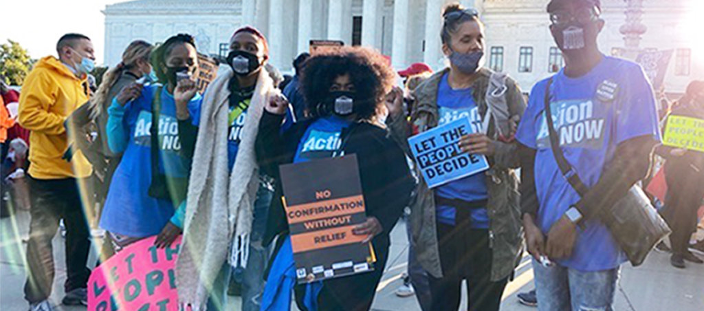 A group of people at a protest wearing "Action Now" shirts.