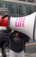 Man with bullhorn that says pro-life on it screaming at woman at anti abortion protest