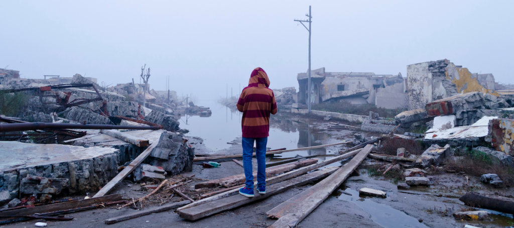 person standing amongst debrief from a tornado or hurricaine